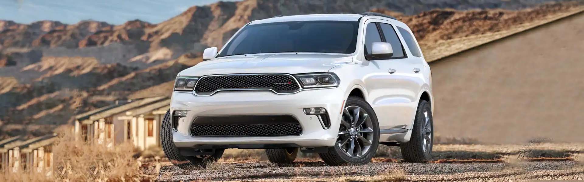 Front view of a white 2021 Dodge Durango parked on a gravel road in a desert landscape.