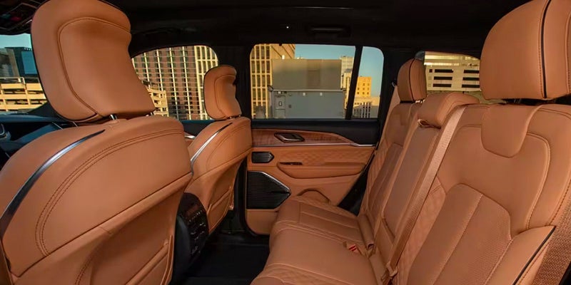 Interior view of a car with tan leather seats and wood-paneled door trim, buildings visible through the windows.