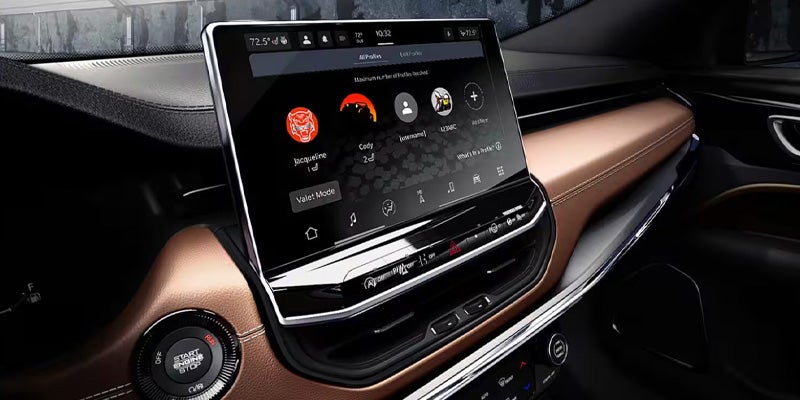 The interior of a car, showing the infotainment system displaying user profiles and climate controls on a brown and black dashboard.
