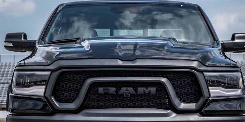 Front view of a dark gray or black Ram truck parked outdoors, showing the bold grille, headlights, and hood.