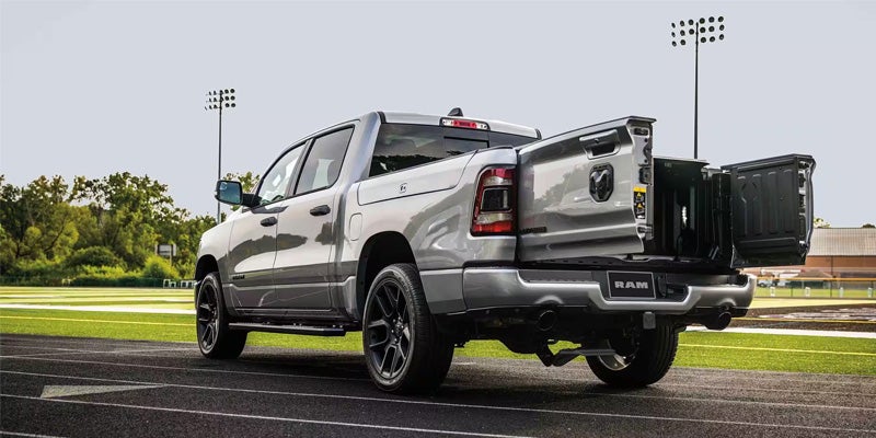 Silver Ram 1500 truck from rear with tailgate open like barn doors, parked on a track.